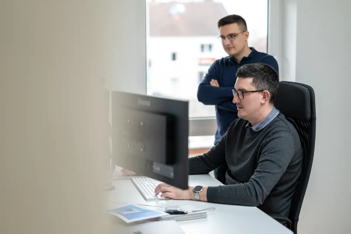 Zwei Mitarbeiter von NEXAS Media richten gemeinsam ein Tracking-Setup am Monitor ein